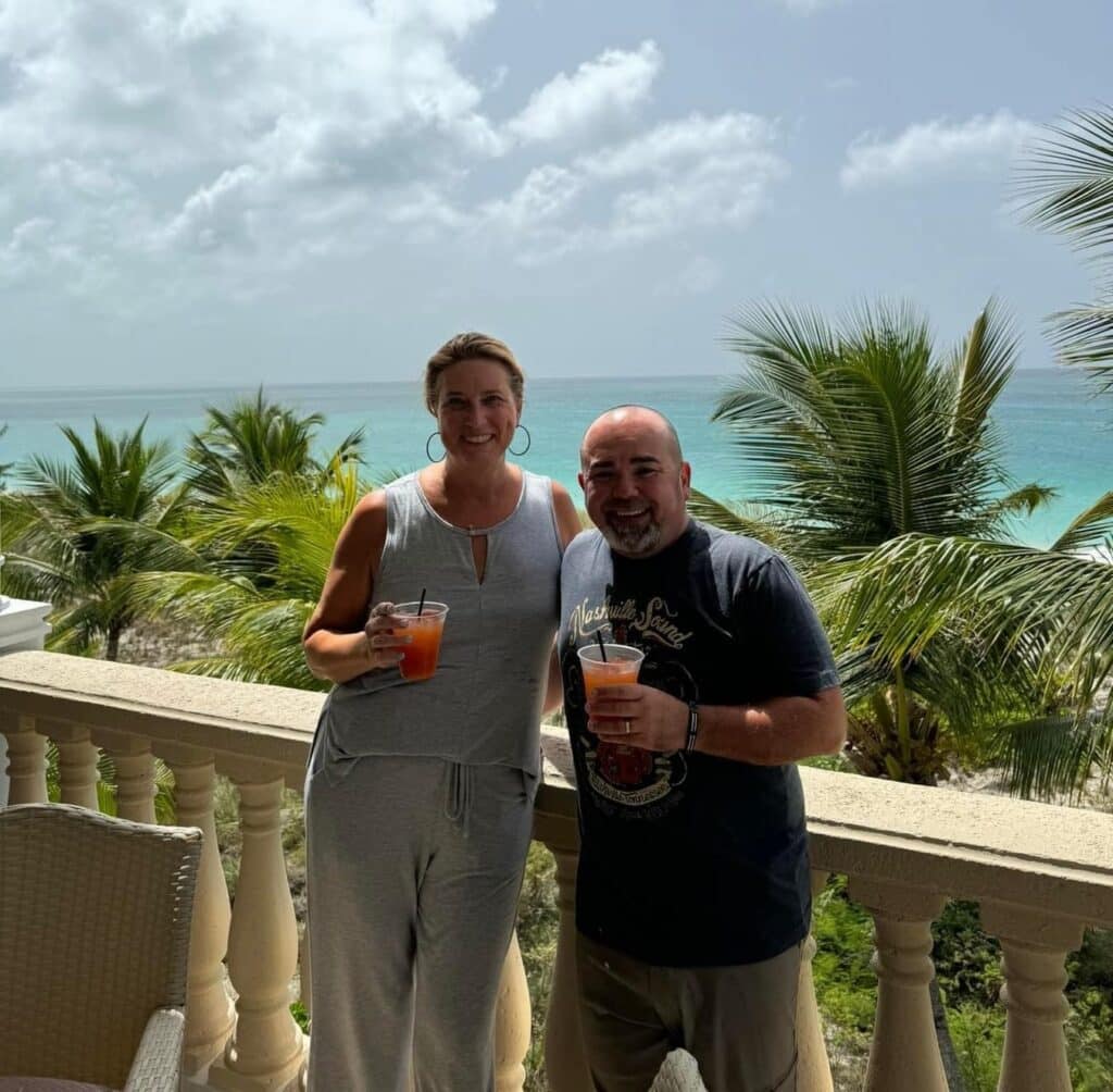 Roger with a colleague enjoying cocktails, with the beach in the background at Turks and Caicos, home of our first international project