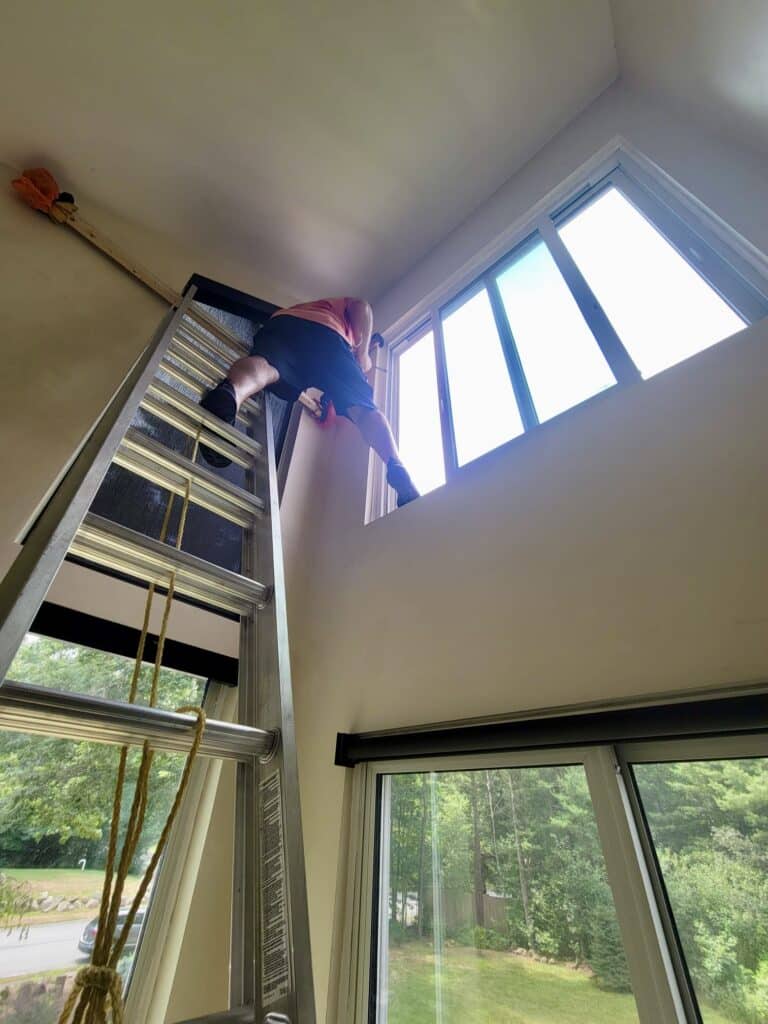 Roger on a tall ladder installing roller shades in a very high window in Boston