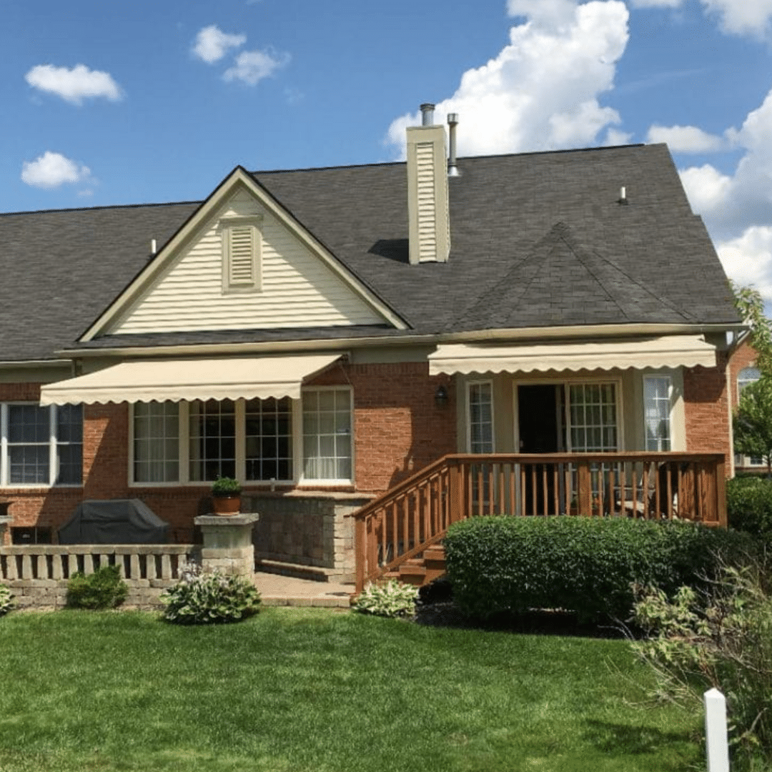 Front of a house showcasing retractable awnings over the windows, designed to provide shade for the balconies from the sun.