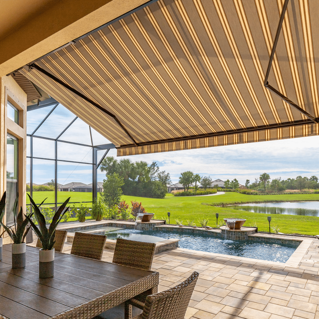 Retractable awning at the back of the house providing shade over a patio area, with a view of the pool in the background.