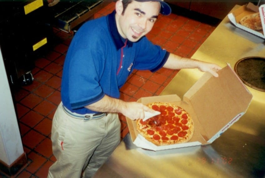 Roger Magalhaes packing a pizza before entering the window treatment industry, showcasing his previous job as a delivery driver.