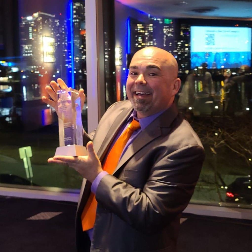 Roger Magalhaes, window treatment installer, proudly holding the 2022 Barry M. Portnoy Immigrant Entrepreneur Award for Business Growth.